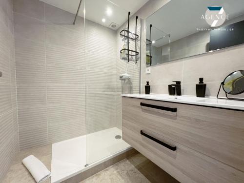 une salle de bain avec une douche en verre et un lavabo dans l'établissement Le Suffren, à Sainte-Maxime