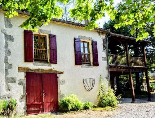 an old house with red doors and a deck at La douce étable - 25 minutes d'Agen in Port-Sainte-Marie
