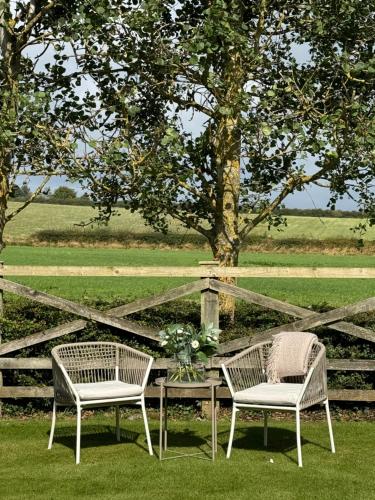 two chairs and a table in front of a fence at Wellsprings Farm - Self-catering studio with private garden in Sacriston