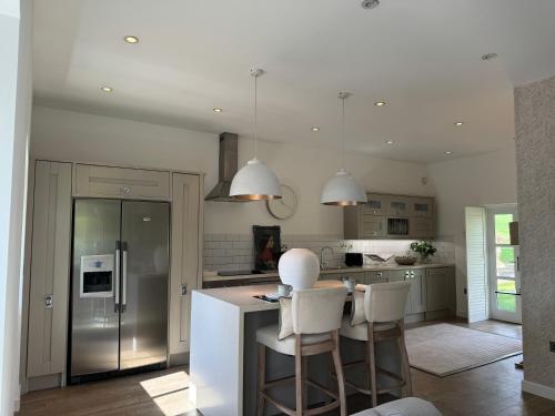 a kitchen with a island with white chairs in it at Wellsprings Farm - Self-catering studio with private garden in Sacriston