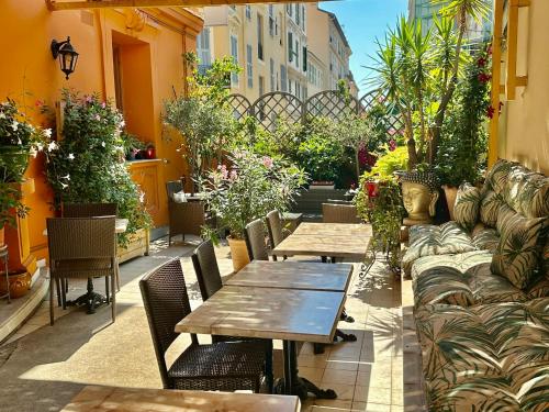 a patio with two tables and chairs and plants at Hotel Lepante in Nice