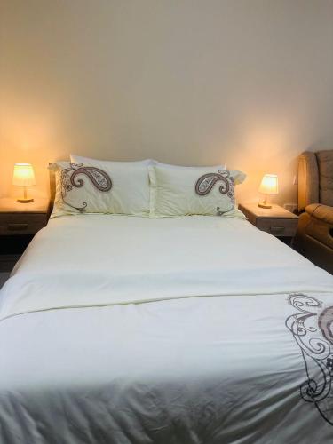 a bedroom with a white bed with two lamps at Luxury Home Lagoon view in Ras al Khaimah