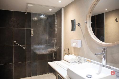 a bathroom with a shower and a sink and a mirror at Hôtel La Casa Pairal in Collioure
