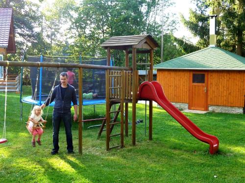 a man and a child standing next to a playground at Ferienhaus Zum Kammergut LINKS oder RECHTS in Langenwolschendorf