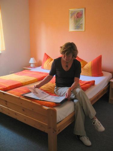 a woman sitting on top of a bed at Ferienhaus Zum Kammergut LINKS oder RECHTS in Langenwolschendorf