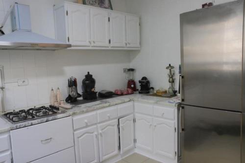 a kitchen with white cabinets and a stainless steel refrigerator at Maison bleue in Dar Salah Bey