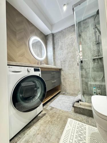 y baño con ducha y lavadora. en RentNow Ultracentral Modern Apartment, en Chişinău