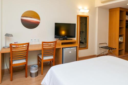 a bedroom with a bed and a desk with a television at Mercure Sao Jose dos Campos in São José dos Campos