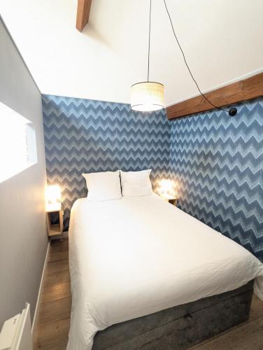 - une chambre avec un lit blanc et un mur bleu dans l'établissement Bel Appartement T1Bis en centre ville de Cholet, à Cholet