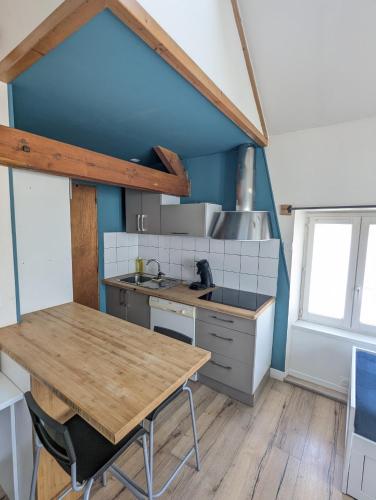une cuisine avec une table en bois et un mur bleu dans l'établissement Bel Appartement T1Bis en centre ville de Cholet, à Cholet