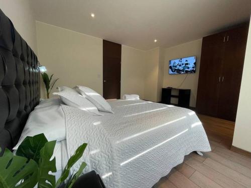 a bedroom with a white bed with a tv on the wall at Amplio y comodo apartamento in Calacala