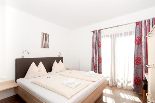 a bedroom with a bed with white sheets and a window at Restaurant - Café - Pension HASSLER in Berg im Drautal