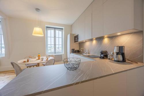 - une cuisine blanche avec un comptoir et une table dans l'établissement Le Royal - Spacieux 3 pièces, à Dinard
