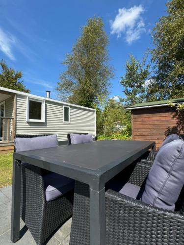 a black table and chairs in a backyard at Low Budget - 4 persoons chalet aan het Lauwersmeer in Lauwersoog