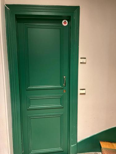 une porte verte avec un bouton rouge sur elle dans l'établissement Appartement entier aux Abbesses - Montmartre - Flat in Montmartre, à Paris