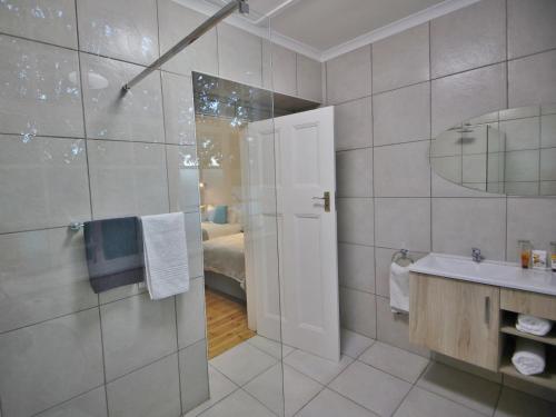 a bathroom with a shower and a sink and a mirror at Lilibet Lodge in Graaff-Reinet
