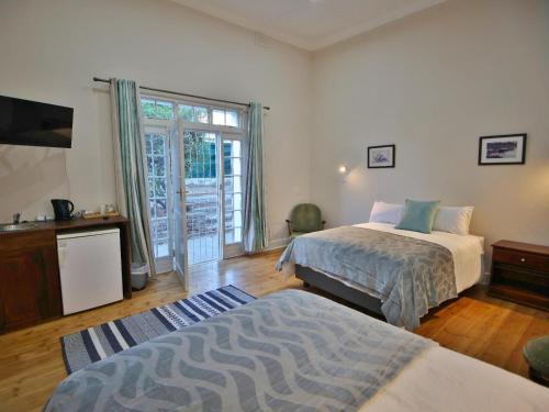 a bedroom with two beds and a sliding glass door at Lilibet Lodge in Graaff-Reinet