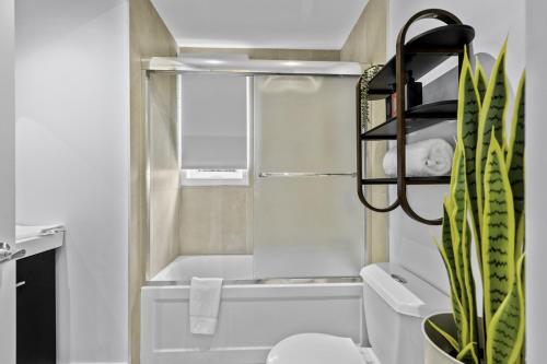 a bathroom with a white tub and a toilet and a plant at Renovated 2-Bedroom Haven by Jean Talon Market in Montréal