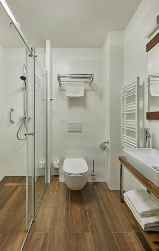 a white bathroom with a toilet and a sink at Impresja Art Resort in Duszniki Zdrój