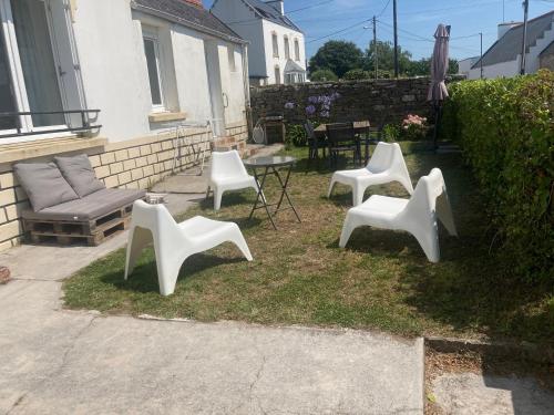 4 chaises blanches et une table dans la cour dans l'établissement Maison de famille vue mer- 4 chambres, 8 personnes, à Plouhinec