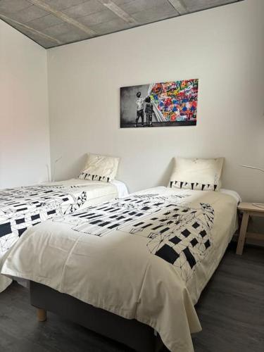 a bedroom with two beds and a painting on the wall at BeliHouse in Trafaria