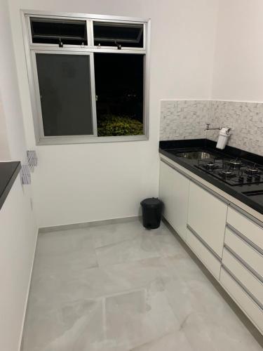 a white kitchen with a sink and a window at Ed Parati 2 quartos Praia do Morro - Guarapari in Guarapari
