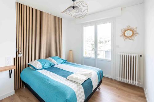 a bedroom with a bed with blue sheets and a window at T2 parking gratuit plus 2 balcons in Aix-les-Bains