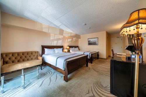 a hotel room with two beds and a couch at Fullerton Manor Inn in Niagara Falls