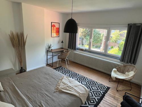 a bedroom with a bed and a desk and windows at Maison proche de Pairi Daiza in Soignies