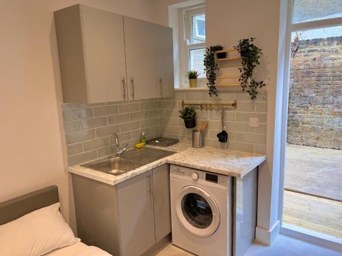 a kitchen with a sink and a washing machine at Skyline Studios Maida-Vale in London