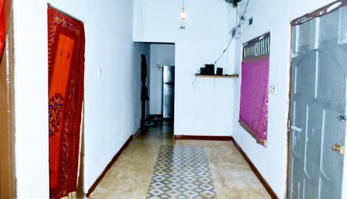 a hallway with a red door and a tile floor at Nimal's white house in Nilaveli
