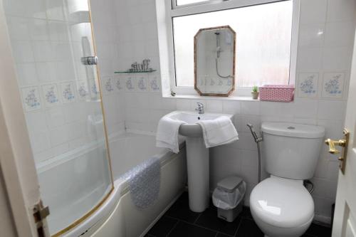 a bathroom with a toilet and a sink and a shower at 3 bed home sleeps 8 people located 1 min from train stop - Otley Terrace in Oldham