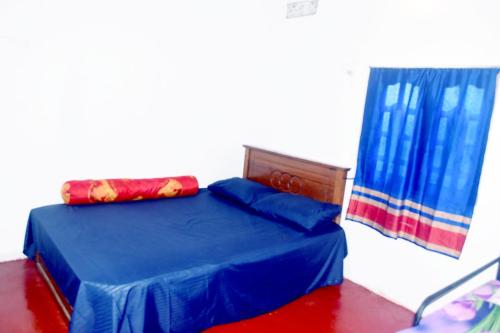 a bedroom with a blue bed and a window at Nimal's white house in Nilaveli