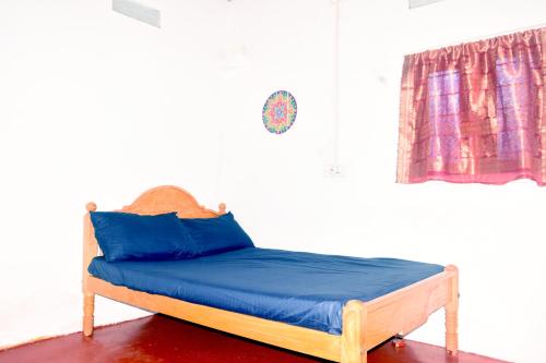 a bed with blue pillows in a room with a window at Nimal's white house in Nilaveli