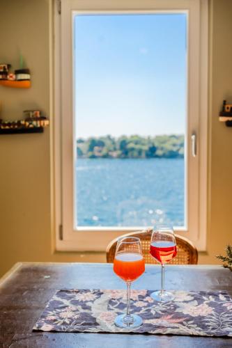 two glasses of wine sitting on a table with a window at Mediterraneo Seaview Apartments in Rovinj