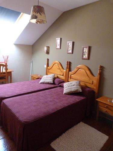 a bedroom with a large wooden bed with purple sheets at Hotel Mestas in Arenas de Cabrales
