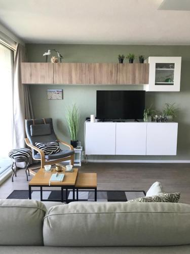 a living room with a couch and a tv at Zee en Strand in De Panne