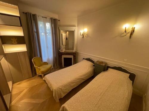 - une chambre avec deux lits, une chaise et un miroir dans l'établissement Appartement Le Joséphine avec jardin privatif, à Rueil-Malmaison