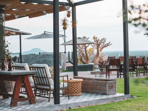 a patio with chairs and tables with a view of the ocean at Otjiwa Mountain Lodge in Otjiwarongo