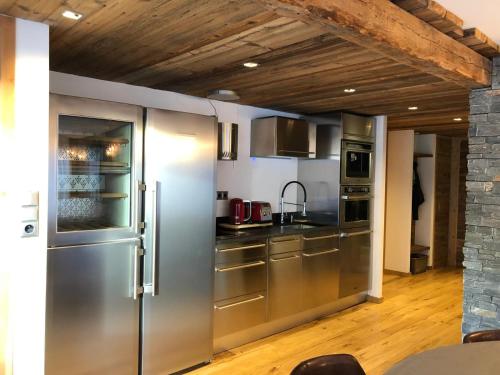d'une cuisine équipée d'appareils en acier inoxydable et d'un plafond en bois. dans l'établissement Luxe au Cœur de la Station, à Huez