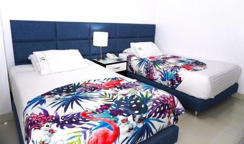 a hotel room with two beds with colorful blankets at Hotel Bolivariana Plaza Medellin in Medellín