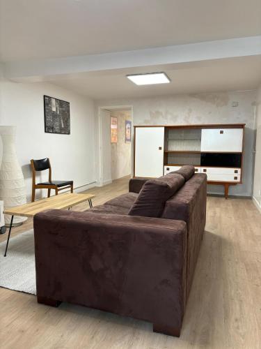 un salon avec un canapé marron et une table dans l'établissement Maison Spacieuse en Ville, à Poitiers