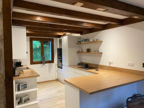 Il comprend une cuisine dotée de comptoirs blancs et de plafonds en bois. dans l'établissement Chalet Avenir, à Saint-Jean-dʼAulps