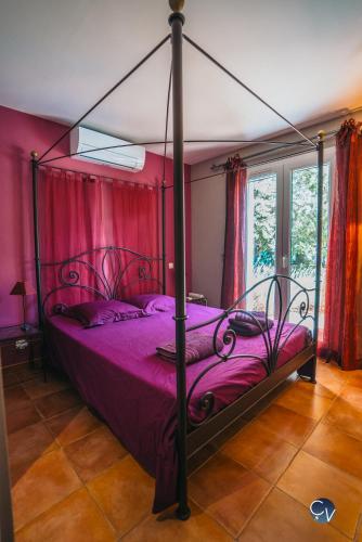 a bedroom with a canopy bed with purple sheets at Les Baragnasses in Saint-Siffret
