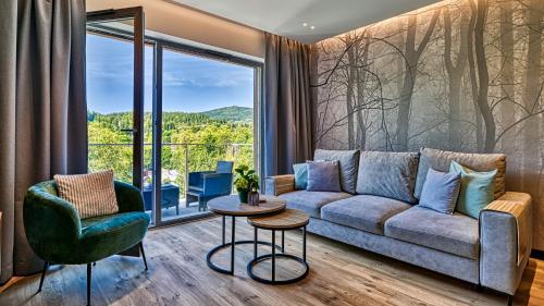 a living room with a couch and a large window at Apartamenty z basenem i saunami STONE HILL RESORT II VIP Centrum by Royal Aparts in Szklarska Poręba