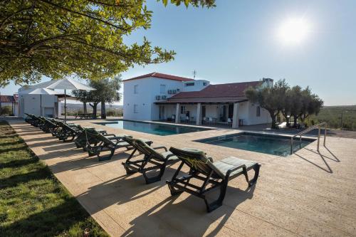 a row of chairs sitting next to a swimming pool at Passo do Lobo - Turismo Rural in Moura