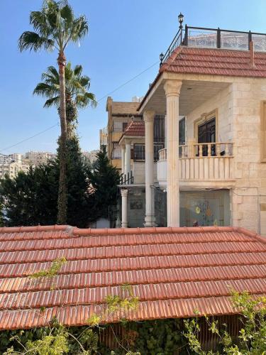 a house with a palm tree in front of it at Classy 3 Bedroom Apartment in Amman in Ţāb Kirā‘