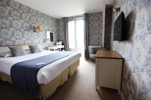 - une chambre avec un grand lit et du papier peint bleu dans l'établissement Hôtel Villa Flornoy Pornichet Baie de la Baule, à Pornichet