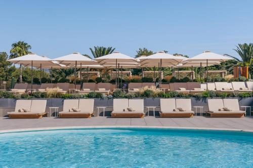 a pool at a resort with lounge chairs and umbrellas at ME Sitges Terramar in Sitges