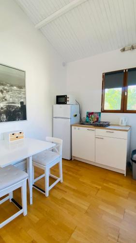 une cuisine blanche avec une table et un réfrigérateur dans l'établissement Le Chalet Pignantais avec option Jacuzzi, à Pignans